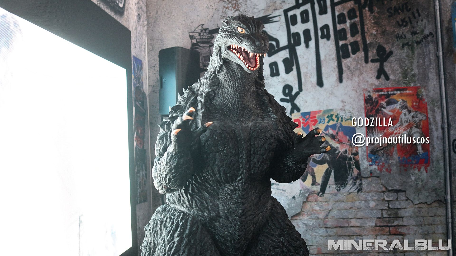 Godzilla in front of an old graffitied wall.